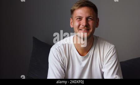 Happy Young Man Watching TV While Relaxing In Bedroom At Home Stock Photo