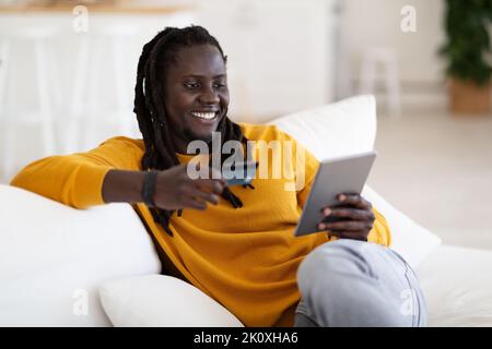 Smiling Black Man Shopping Online With Digital Tablet And Credit Card Stock Photo