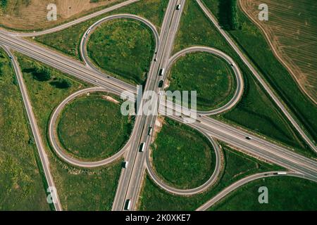 Clover or daisy type of road junction. Aerial top down view of beautiful highway road junction in clover shape at summer day. Lorry truck and semi-truck on highway. Logistic concept Stock Photo