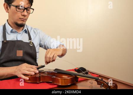 Latin male worker fixing the strings of a violin in a workshop Stock Photo