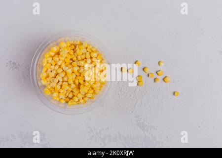 Top view composition of plastic bowl with frozen sweet corn on a white concrete background Stock Photo