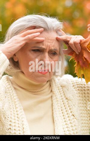 Senior sad woman in the park in autumn Stock Photo