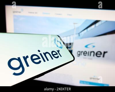 Smartphone with logo of Austrian plastics company Greiner AG on screen in front of business website. Focus on center-right of phone display. Stock Photo