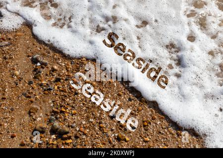 Seaside text cut out on both pebble beach and lapping waves  Stock Photo
