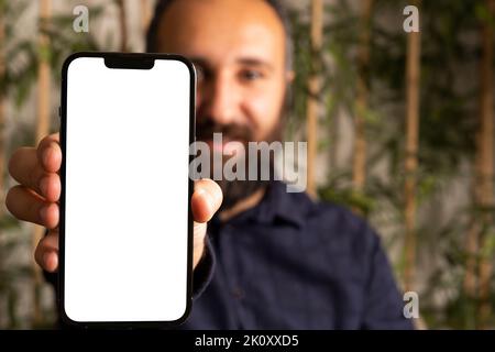 Showing modern smartphone, portrait of caucasian bearded man showing modern smartphone. Selective focus on hand. Mobile phone mock up. Stock Photo