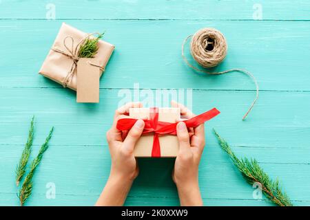 Christmas background with gift boxes, skein of rope and cypress branches on teal blue wooden table. Preparation for holidays. Top view, flat lay. Girl Stock Photo