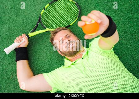Tennis player sitting on grass having a rest outdoors Stock Photo