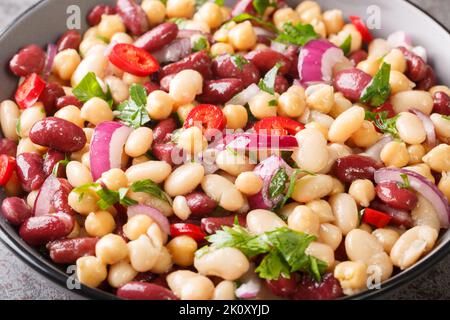 Delicious vegetable salad three beans with chili peppers and red onions close-up in a bowl on the table. Horizontal Stock Photo