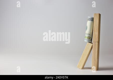 There is a rolled up 100 dollar bill on a wooden cubes on a light background. Currency concept Stock Photo
