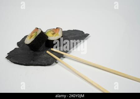 two pieces of sushi in a blackboard plate with chopstick, ginger and wasabi Stock Photo