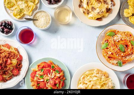 Italian pasta dishes forming a frame for copy space, overhead flat lay shot. Pastas with meat, vegetables, seafood, chicken and mushrooms, wine Stock Photo