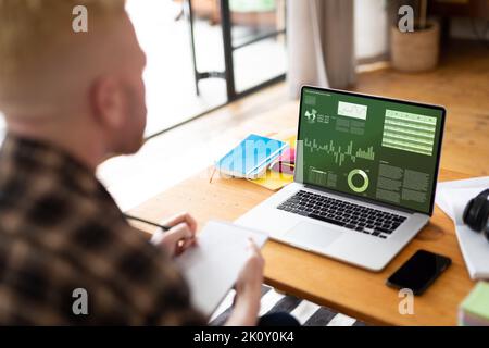 Albino african american man taking notes and using laptop, data processing on screen Stock Photo