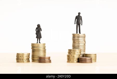 Gender Wage gap concept. Man and woman figurines standing on top of the pile of coins. Copy space Stock Photo