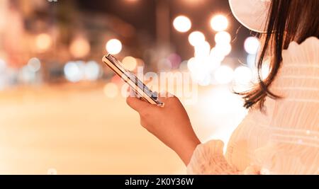 Close-up image of female hand using mobile smartphone at night city street. concept of searching or social networks. Stock Photo