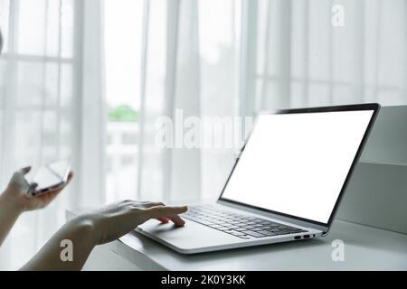 Woman hands using laptop with blank screen on white table at home or office. Stock Photo