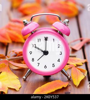 Alarm clock and orange autumn leaves, back to school, fall concept Stock Photo