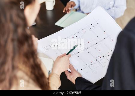 Close-up of group of architects examining architectural project in team at table Stock Photo