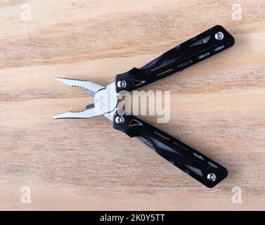 Top view of multi functional pliers open on a wood background top view. Stock Photo