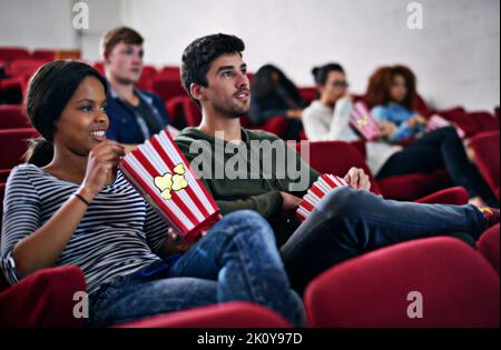 Catching the latest on the big screen. people enjoying watching a movie in a cinema. Stock Photo