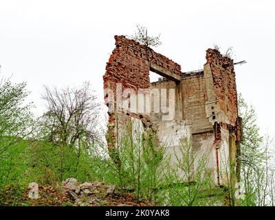 Wall of a destroyed brick building on cloudy day. Fragment of the wall of the destroyed building. Stock Photo