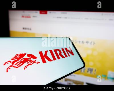 Smartphone with logo of Japanese Kirin Brewery Company Limited on screen in front of business website. Focus on center of phone display. Stock Photo