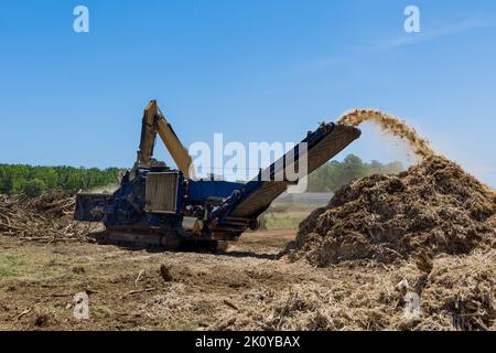 The land on which a housing development is going to be built has roots that are being shred into chips by an industrial shredder machine Stock Photo