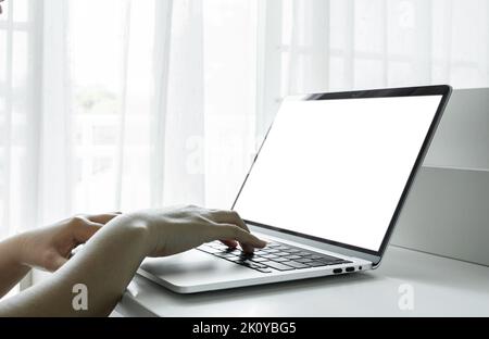 Woman hands using laptop with blank screen on white table at home or office. Stock Photo
