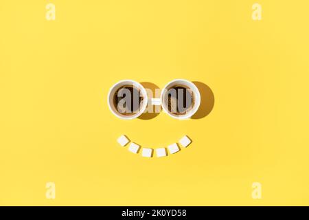 Relax morning coffee time with eyes made of two cups of coffee and smile made of sugar cubes. Stock Photo