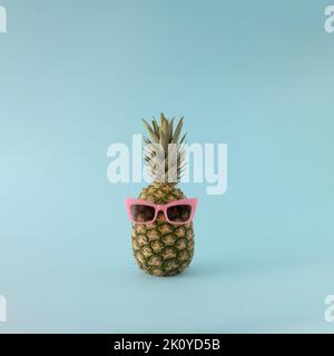 Summer background - fresh pineapple with pink sunglasses on blue background. Stock Photo