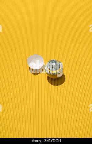 Disco ball in a cracked egg shell on yellow background. Minimal concept. Stock Photo