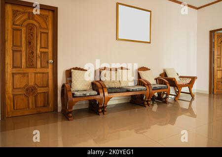 Stylish room interior with comfortable wood furniture with empty picture frame on white wall Stock Photo