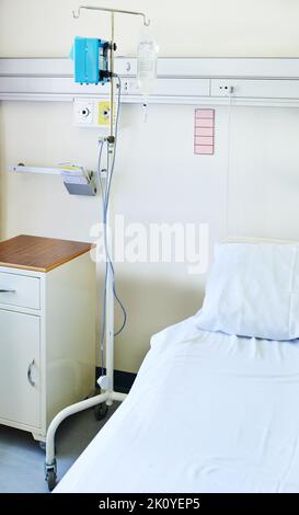 Standing by to be of assistance. Interior shot of a bed and an IV stand in a hospital ward. Stock Photo