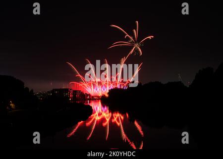 Fireworks above the river canal Roeselare-leie.  Reflections in water of fireworks in flanders Izegem.  Commercial firework photos from in Belgium Stock Photo