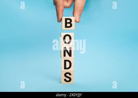 Concept of bonds. Businessman puts wooden blocks with the word Bonds. Equivalent loan. Unsecured and secured bonds. Bonds increasing concept. Copy Stock Photo