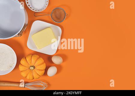 Ingredients and baking tools for pumpkin pie on orange background with copy space Stock Photo