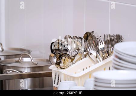 Clean spoons and forks in a stand on the table Stock Photo