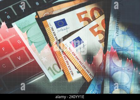 Economic crisis in the European Union. Euro money banknotes on a laptop with falling chart hologram Stock Photo