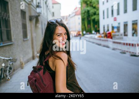 Smiling young woman carrying a backpack in the city Stock Photo