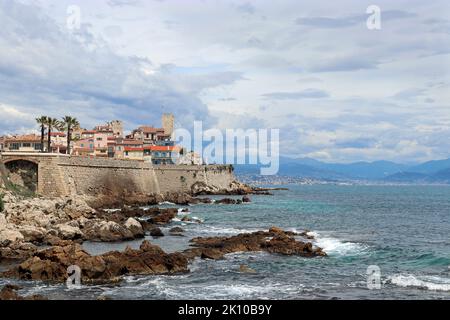 A distant view of the coastal city of Antibes, showing the old town enclosed by 16th century ramparts rising above the sea. French Riviera. Stock Photo