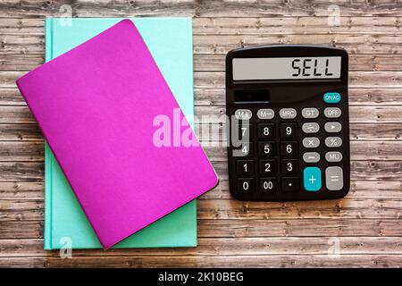 SELL text in on calculator display and notepads on wooden background Stock Photo
