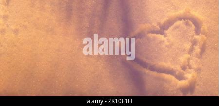 A heart painted on a shiny pink surface of snow in the light of evening lanterns (contour, top view). Banner. Space for text. Copy space. Stock Photo
