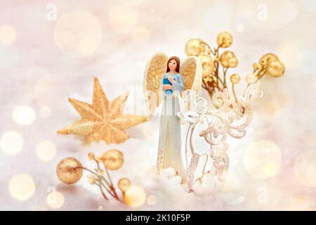 a guardian angel in the snow in blue clothes with a book with golden festive decorations - a star, a deer. postcard. A Christmas tale. Stock Photo