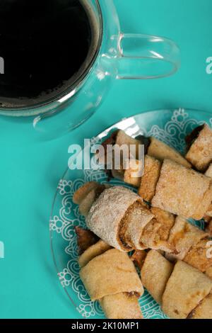 Rolls with cinnamon. Croissants with cinnamon. They lie on a saucer. There is a cup of coffee next to it. Light green background. Shot close-up. Stock Photo