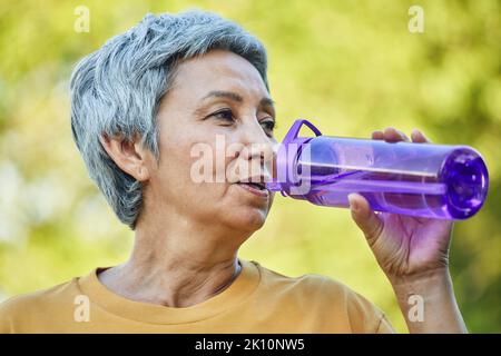 Close up image attractive mature woman holds plastic reusable bottle make sip drinking still mineral water during morning work out or stroll in summer Stock Photo