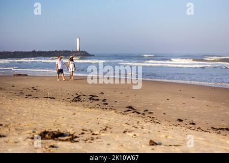 Couple of prospective parents holding hands, walking on the beach Stock Photo