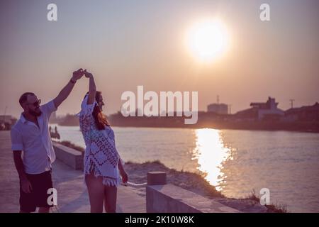 Pregnant couple in love dancing at sunset on the platform of Praia dos Molhes in Torres in Rio Grande do Sul. Stock Photo