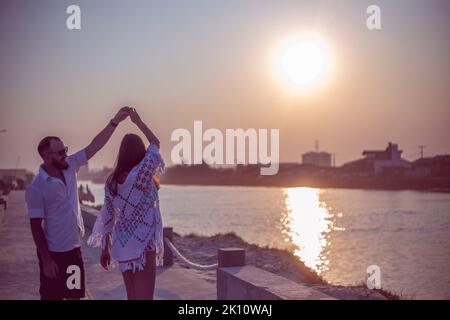Pregnant couple in love dancing at sunset on the platform of Praia dos Molhes in Torres in Rio Grande do Sul. Stock Photo