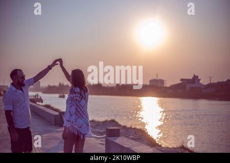 Pregnant couple in love dancing at sunset on the platform of Praia dos Molhes in Torres in Rio Grande do Sul. Stock Photo