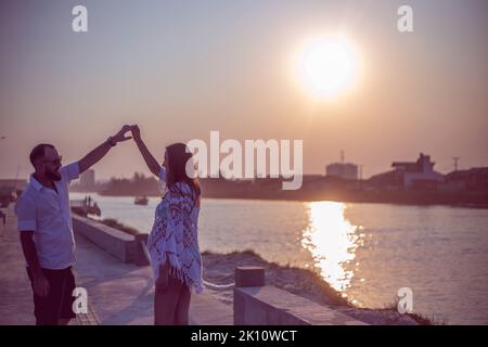 Pregnant couple in love dancing at sunset on the platform of Praia dos Molhes in Torres in Rio Grande do Sul. Stock Photo