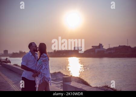 Pregnant couple in love dancing at sunset on the platform of Praia dos Molhes in Torres in Rio Grande do Sul. Stock Photo